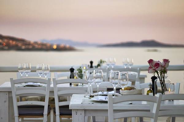 Terrasse des Rocabella Mykonos Art Hotel & Spa mit Blick auf das Meer bei Sonnenuntergang.
