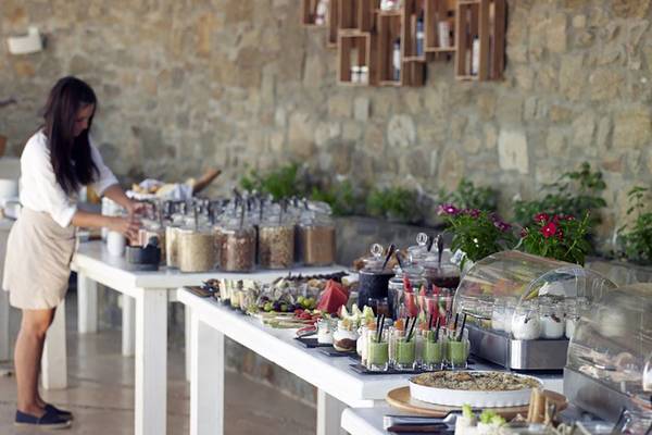 Frühstücksbuffet im Rocabella Mykonos Art Hotel & Spa mit einer Frau, die Essen serviert.