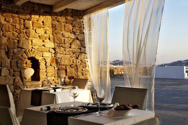 Außenterrasse des Rocabella Mykonos Art Hotel & Spa mit gedeckten Tischen und Blick auf die Umgebung.