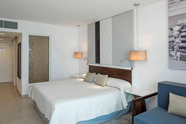 Schlafzimmer im Iberostar Origin Bella Vista Varadero Hotel mit einem großen Bett und einem Nachttisch.