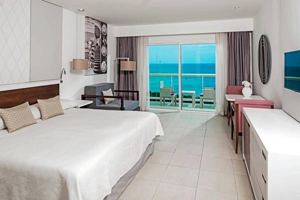 Innenansicht des Iberostar Origin Bella Vista Varadero Hotels mit einem Bett, einem Balkon und Meerblick.