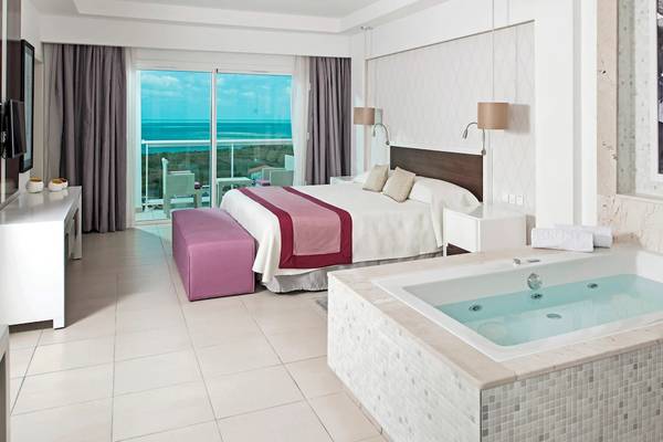 Innenansicht der Suite im Iberostar Origin Bella Vista Varadero mit großem Bett, Jacuzzi und Meerblick.