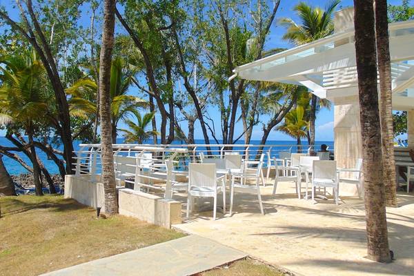 Terrasse des Casa Marina Beach Resorts mit Blick auf den Ozean, umgeben von Palmen und weißen Stühlen.