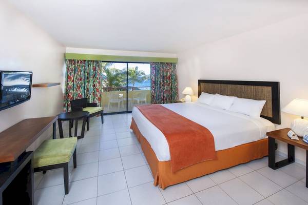Innenansicht eines Zimmers im Casa Marina Beach Resort mit Bett, Schreibtisch, Fernseher und Balkon.