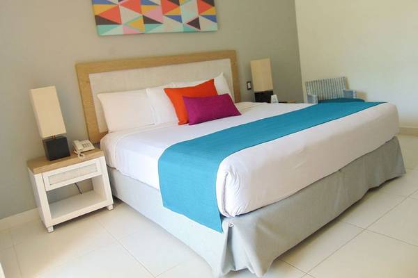Zimmer im Casa Marina Beach Resort mit einem Bett, Kissen und Nachttischen.