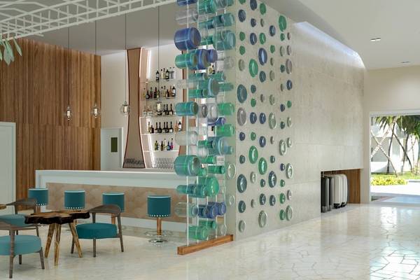 Innenansicht der Bar im Coral Level at Iberostar Selection Bávaro Hotel mit Holzwand, Bartresen, grünen Flaschen und runden Wandkunst.