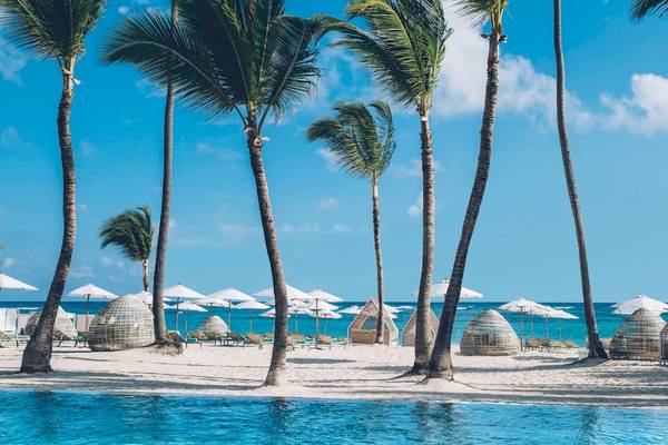 Ein Strand mit weißen Sonnenschirmen und Palmen im Coral Level at Iberostar Selection Bávaro.