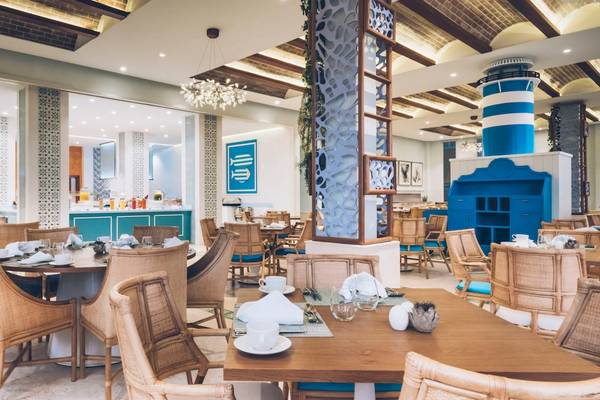 Restaurant-Innenbereich im Coral Level at Iberostar Selection Bávaro mit blauen und weißen Dekorelementen, Holztischen und Stühlen.
