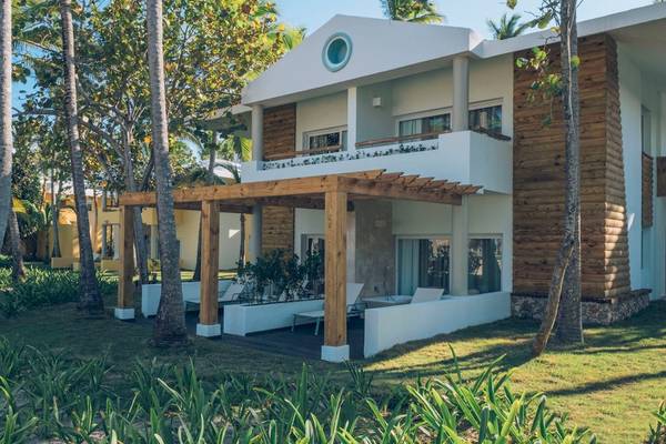 Außenansicht des Coral Level at Iberostar Selection Bávaro Hotels mit Holzveranda und grüner Umgebung