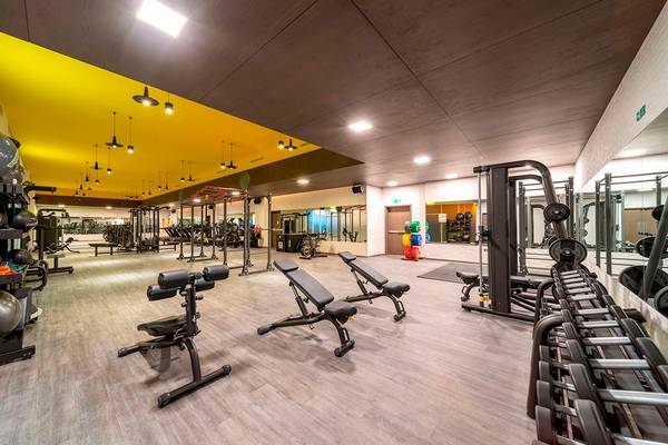 Fitnesscenter im FIVE Jumeirah Village Hotel mit verschiedenen Trainingsgeräten und einer gelben Decke.