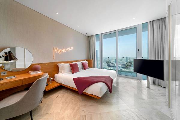 Schlafzimmer im FIVE Jumeirah Village Hotel mit großem Bett, Nachttisch und Aussicht auf die Stadt.
