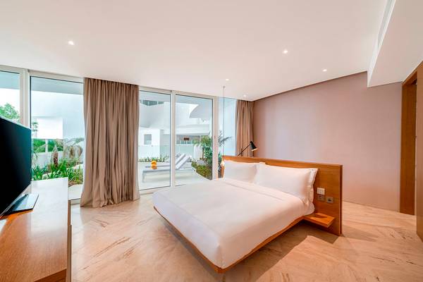Schlafzimmer im FIVE Jumeirah Village Hotel mit Doppelbett, Fernseher und Panoramafenstern.