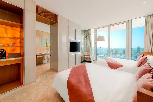 Doppelzimmer-Innenansicht im FIVE Jumeirah Village Hotel mit zwei Betten und Blick auf die Stadt.