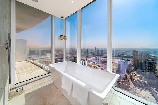 Ein Badezimmer mit einer Badewanne, großen Fenstern und Blick auf die Stadt.