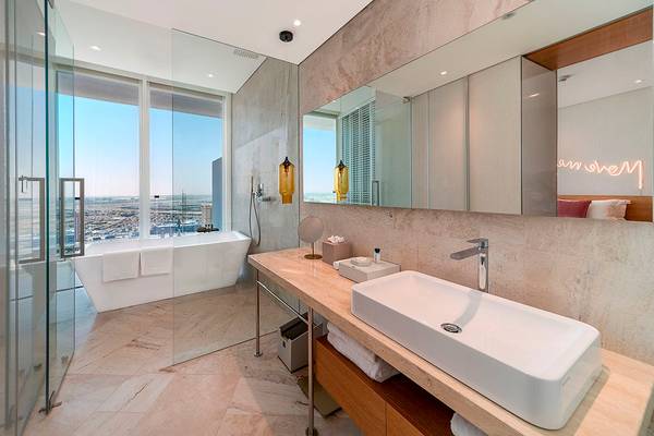 Badezimmer im FIVE Jumeirah Village Hotel mit Badewanne, zwei Waschbecken und Panoramafenstern.