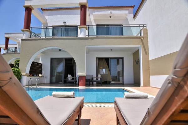 Außenpool des Kresten Royal Euphoria Resorts mit Sonnenliegen und Blick auf die Villa