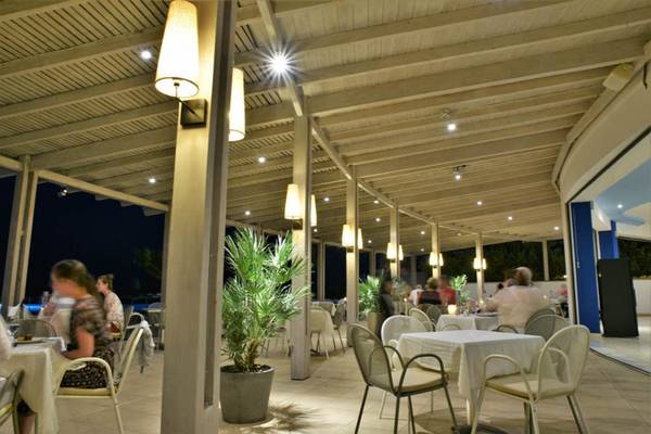 Abendansicht der Terrasse des Kresten Royal Euphoria Resorts mit Gästen an Tischen und Pflanzen.