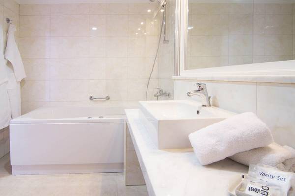 Badezimmer im Kresten Royal Euphoria Resort mit Badewanne, Waschbecken und Toilettenartikeln.