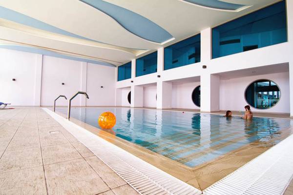 Indoor-Pool im Kresten Royal Euphoria Resort mit zwei Schwimmerinnen und einer schwimmenden Kugel.