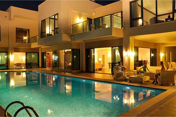 Abendansicht des Susesi Luxury Resorts mit Swimmingpool und Gästen auf der Terrasse.
