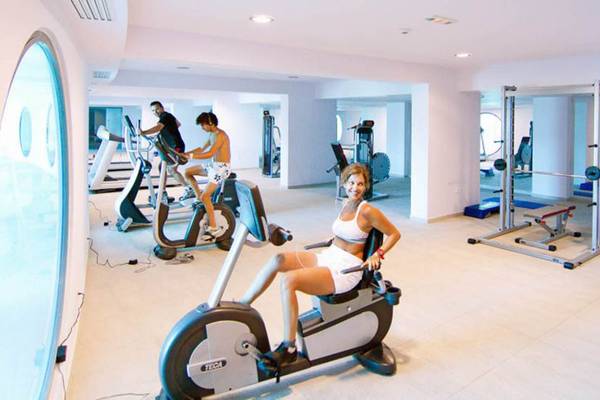 Fitnesscenter im Kresten Royal Euphoria Resort mit einer Frau auf einem Radtrainer.