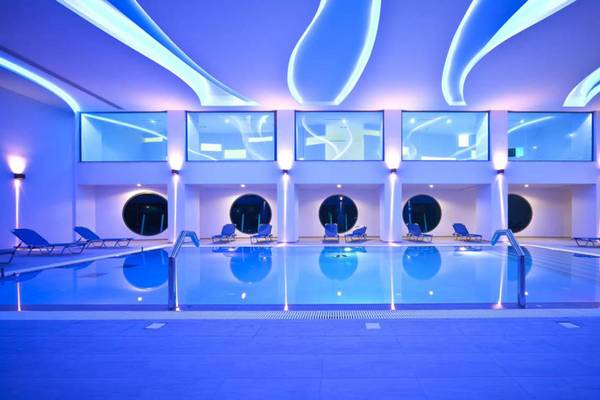 Ein modernes Schwimmbad im Kresten Royal Euphoria Resort mit blauen Leuchten und Lounge-Stühlen.