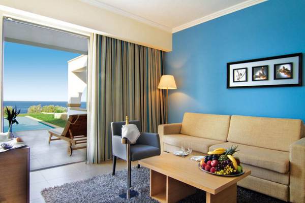 Innenansicht eines Zimmers im Kresten Royal Euphoria Resort mit Sofa, Tisch, Sessel und Meerblick.