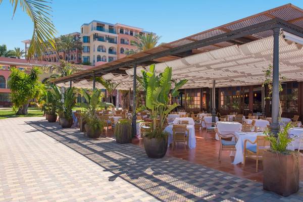 Restaurantterrasse des Iberostar Selection Anthelia Hotels mit Tischen und Stühlen unter einem Pergoladach.