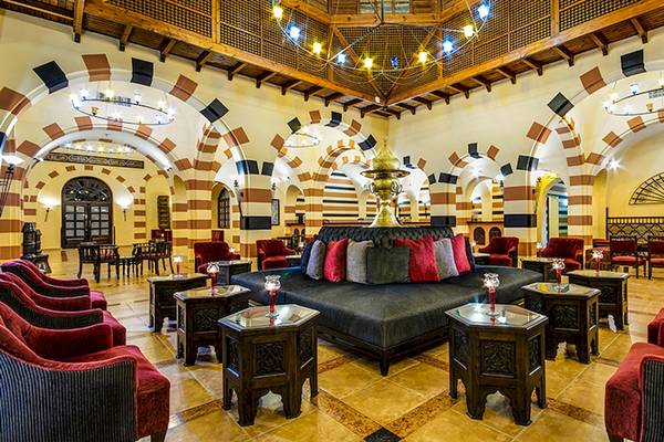 Loungebereich im Jaz Makadi Oasis Resort & Club mit rotem und schwarzen Möbeln und goldener Wasserfontäne.