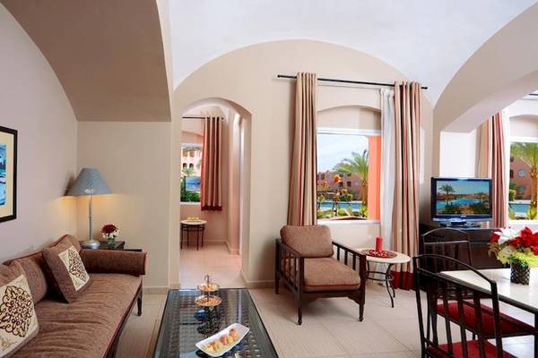 Wohnzimmer des Jaz Makadi Oasis Resort & Club mit Sofa, Lampe, Fernseher und Tisch.