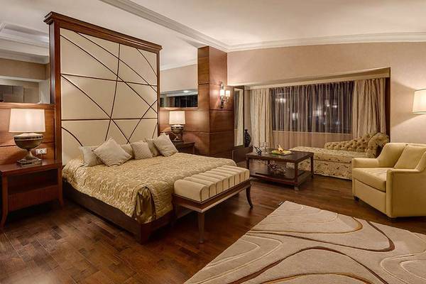 Schlafzimmer im Susesi Luxury Resort mit einem großen Bett, Beistelltischen, Lampen, einem Sofa und einem Fenster mit Vorhängen.