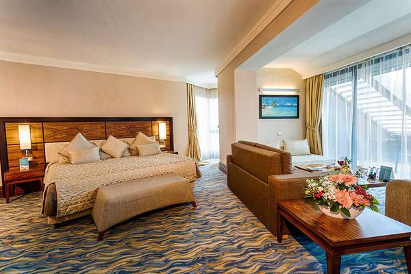 Schlafzimmer im Susesi Luxury Resort mit großem Bett, Sofa und Blumenarrangement.