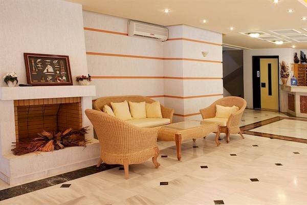 Lobby des Dedalos Beach Hotels mit Kamin, Sofas und Rezeptionstresen.