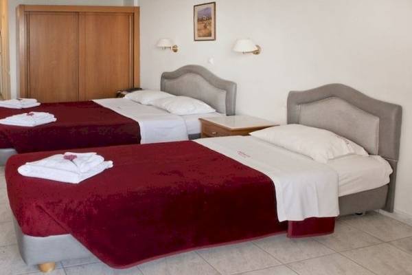 Zwei Doppelbetten mit roten und weißen Bettdecken in einem Hotelzimmer.