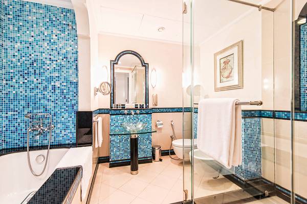 Ein Badezimmer im Habtoor Grand Resort & Spa mit blauen Fliesen und einem Glasspiegel.