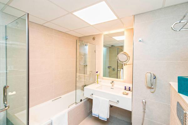 Badezimmer im Habtoor Grand Resort & Spa mit Badewanne, Dusche, Spiegel und Toilettenartikeln