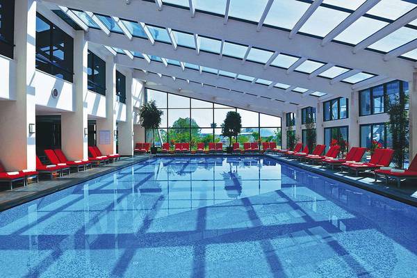 Innenpool des Susesi Luxury Resorts mit roten Sonnenliegen und Glasdach.