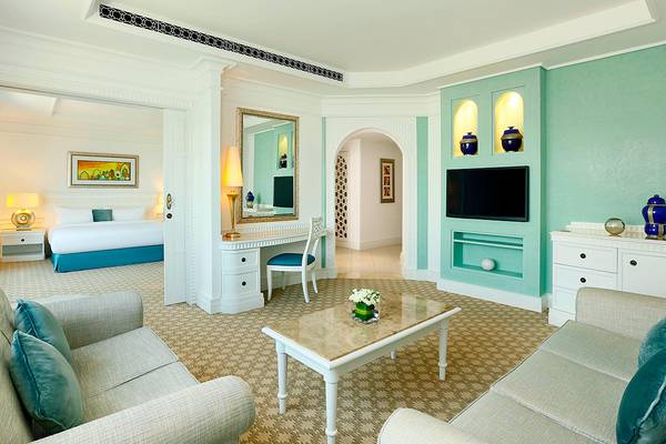 Innenansicht der Suite im Habtoor Grand Resort & Spa mit Wohnzimmer, Schreibtisch und Schlafzimmerbereich.