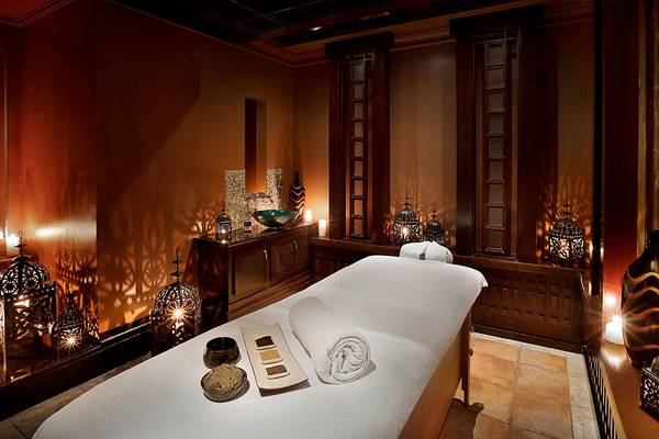 Massageraum im Habtoor Grand Resort & Spa mit einem weißen Behandlungsbett und dunklem Ambiente.