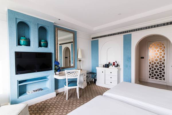 Schlafzimmer im Habtoor Grand Resort & Spa mit blauen Wänden, Fernseher und Schreibtisch.