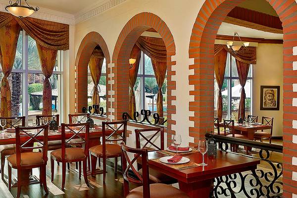 Innenbereich des Restaurants im Habtoor Grand Resort & Spa mit roten Stühlen und Tischen.