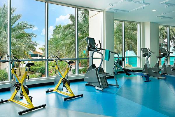 Fitnessstudio im Habtoor Grand Resort & Spa mit großen Fenstern und Trainingsgeräten.