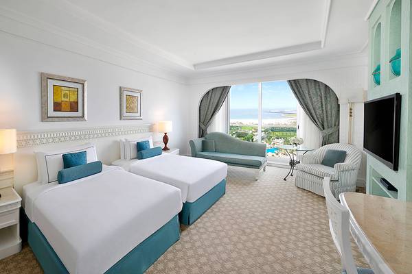 Doppelzimmer im Habtoor Grand Resort & Spa mit Meerblick, zwei Betten, Sofa und Fernseher.