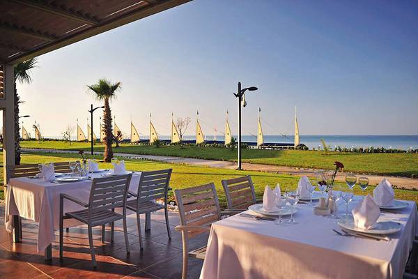Außenbereich des Susesi Luxury Resorts mit zwei gedeckten Tischen und Blick auf das Meer.