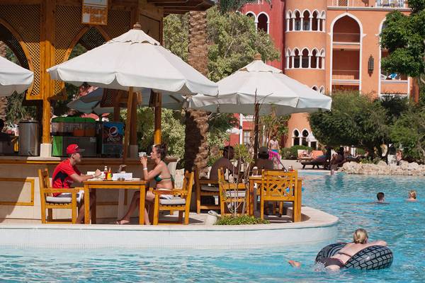 Besucher sitzen an Tischen und trinken am Pool-Bar des Grand Resort Hurghada.