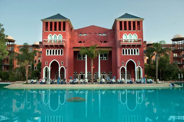 Außenansicht des Grand Resort Hurghada mit roten Gebäuden und Gästen am Pool.