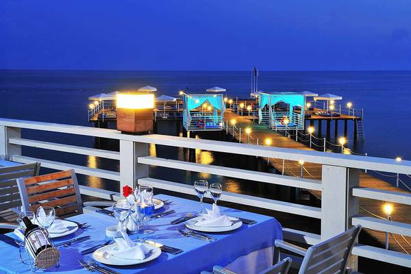 Abendessen auf der Pier im Susesi Luxury Resort mit Blick auf das Meer und blaue Beleuchtung.