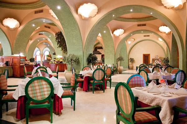 Innenansicht des Restaurants im Grand Resort Hurghada mit grünen und roten gemusterten Stühlen und Tischen.