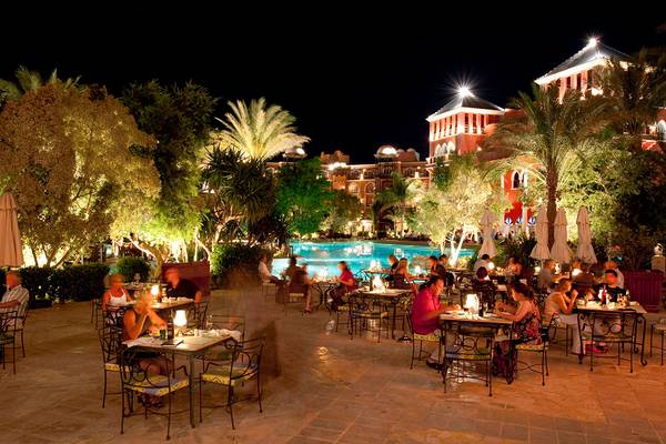 Gäste sitzen bei Nacht auf der Terrasse des Grand Resort Hurghada um einen Pool herum.