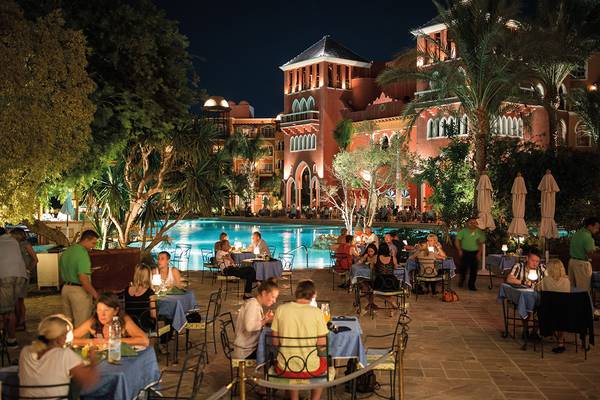 Nachtansicht des Pools und der Außenterrasse des Grand Resort Hurghada mit Gästen, die sitzen und essen.